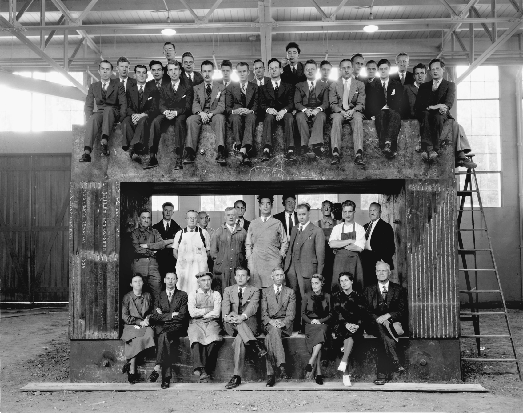 Ernest Lawrence and his team sit atop a giant magnet, a small part of the first cyclotron accelerator.